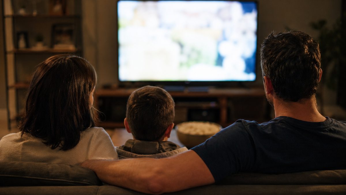 Family watching television together in a warmly lit living room in the evening